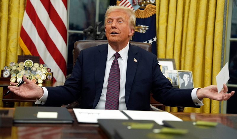 President Donald Trump holds up the letter that former President Joe Biden left for him in the desk as he signs executive orders in the Oval Office of the White House, Monday, Jan. 20, 2025, in Washington. (AP Photo/Evan Vucci)